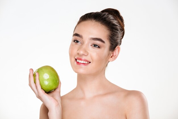 portrait of happy brunette woman holding green apple and looking away