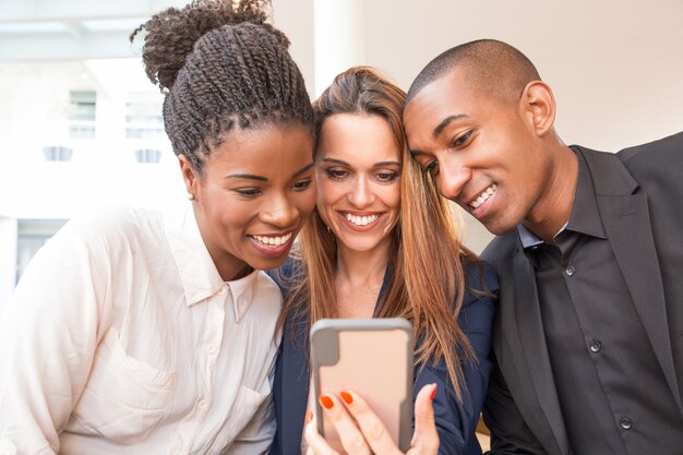 Portrait of happy business colleagues using mobile phone