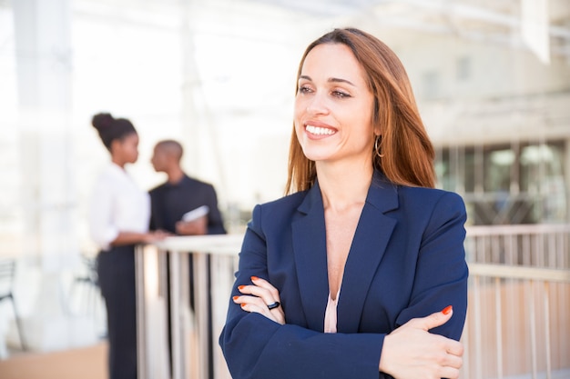 Portrait of happy businesswoman and her employees in background