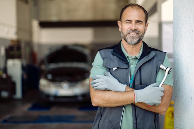 Portrait of happy car service owner with arms crossed at his workshop