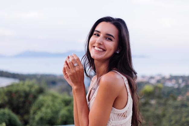 Portrait of happy caucasian calm romantic woman in casual look with long hair wearing earings and necklace on background amazing beautiful view on green mountains