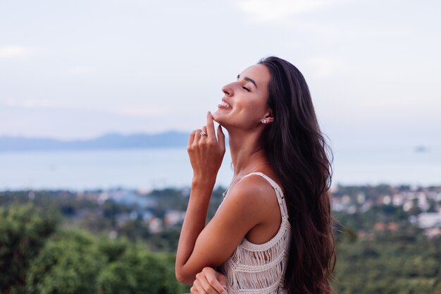 Portrait of happy caucasian calm romantic woman in casual look with long hair wearing earings and necklace on background amazing beautiful view on green mountains