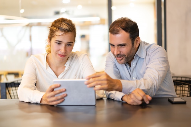 Free photo portrait of happy colleagues browsing on digital tablet at cafe