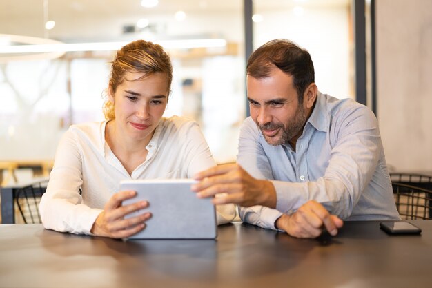 Portrait of happy colleagues browsing on digital tablet at cafe