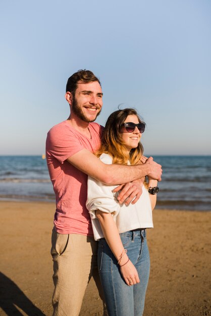 Portrait of a happy couple standing near the seashore looking away at beach