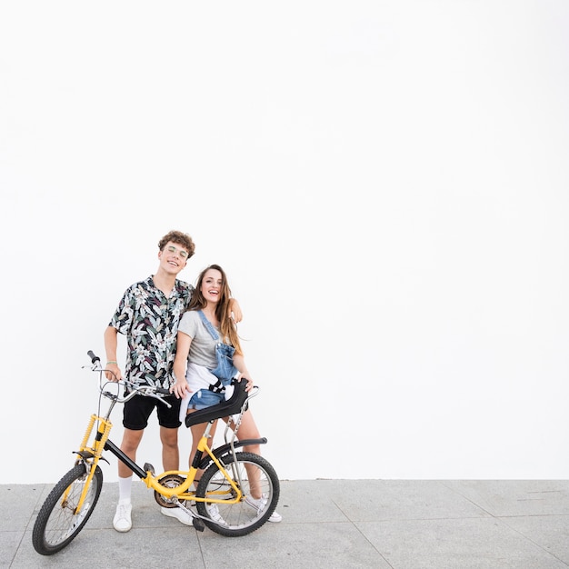 Free photo portrait of a happy couple with bicycle standing on sidewalk