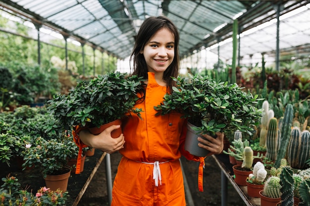 Free Photo portrait of a happy female gardener holding two potted plants