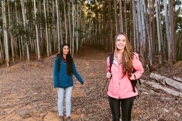 Portrait of a happy female hiker with her friend in forest