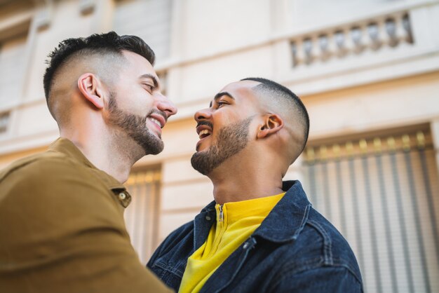 Portrait of happy gay couple spending time together and hugging in the street.