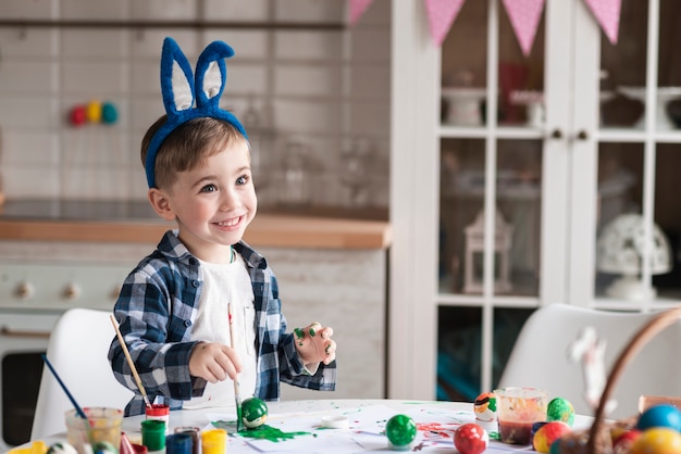 Portrait of happy little boy painting easter eggs