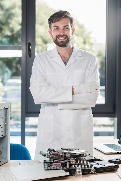 Free photo portrait of a happy male technician with crossed arms standing in workshop