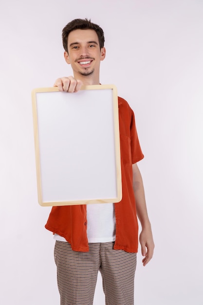 Portrait of happy man showing blank signboard on isolated white background