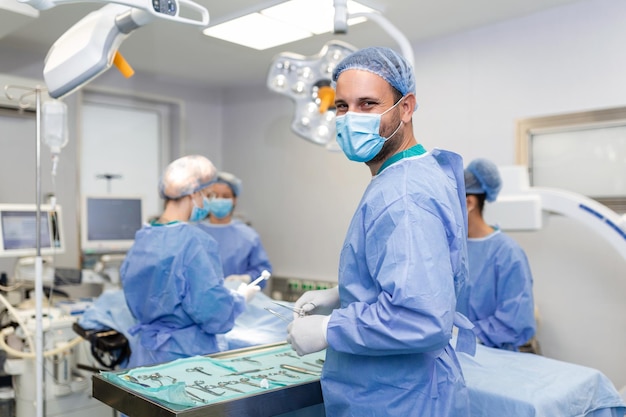 Free photo portrait of happy man surgeon standing in operating room ready to work on a patient male medical worker in surgical uniform in operation theater