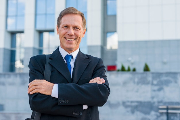 Free photo portrait of a happy mature businessman with folded arms