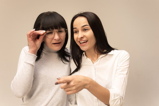 A portrait of a happy mother and daughter at studio on gray