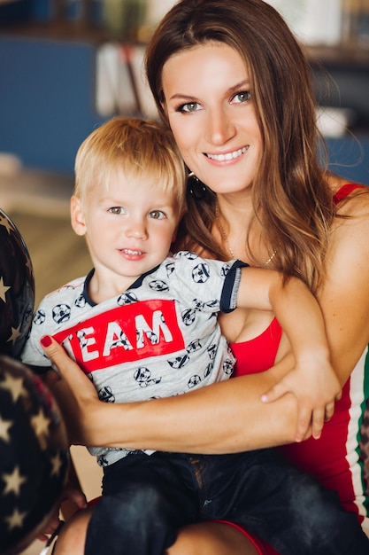 Free Photo portrait of happy mother and son posing together mom hugging her child beautiful woman and cute son looking at camera and smiling pretty kid having blonde hair