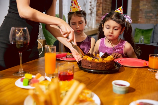 Portrait of happy multiethnic family celebrating a birthday at home. Big family eating cake and drinking wine while greeting and having fun children. Celebration, family, party, home concept.