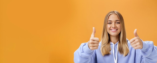 Free photo portrait of happy optimistic woman showing thumbs up gesture and smiling supportive with cheerful lo