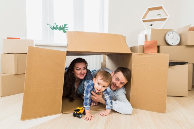 Portrait of a happy parents playing with toddler boy inside the cardboard box