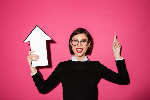 Portrait of a happy pretty businesswoman with arrow pointing up