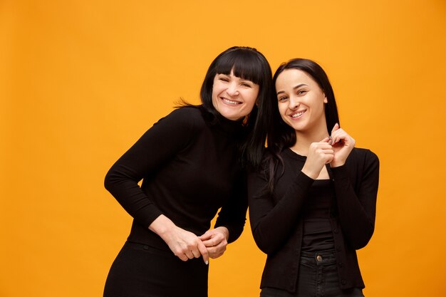 A portrait of a happy smiling mother and daughter at studio on gold