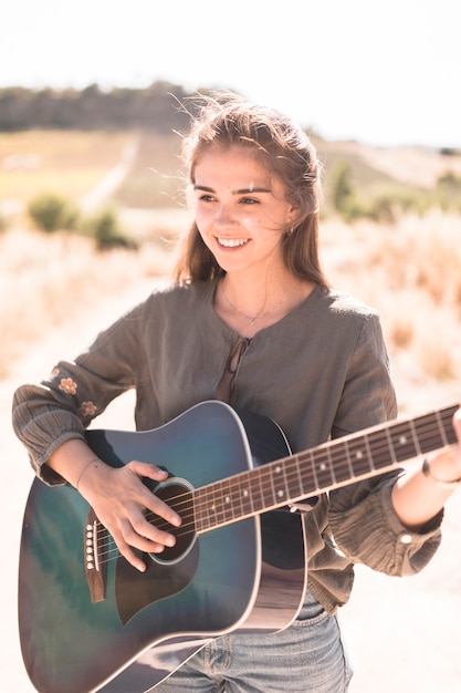 Portrait of a happy teenage girl playing guitar