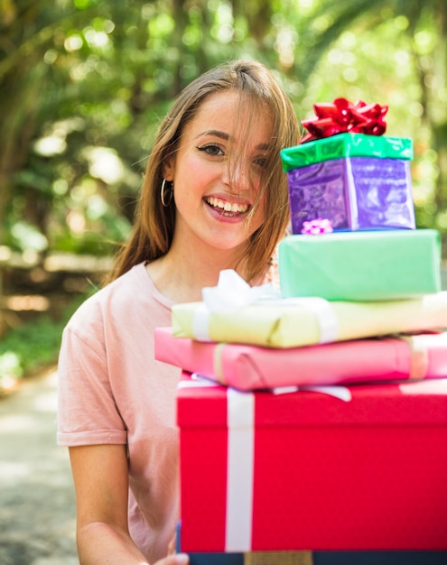 Portrait of a happy woman holding stack of gifts