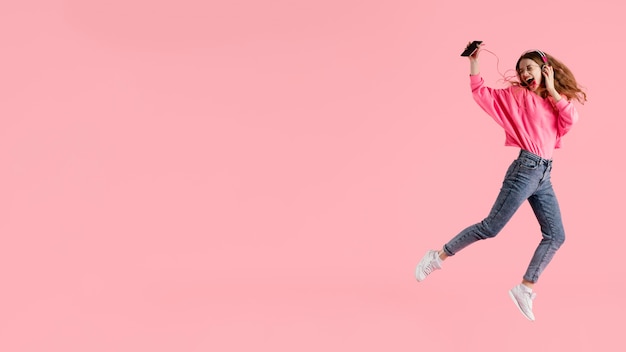 Free Photo portrait happy woman jumping and listening music