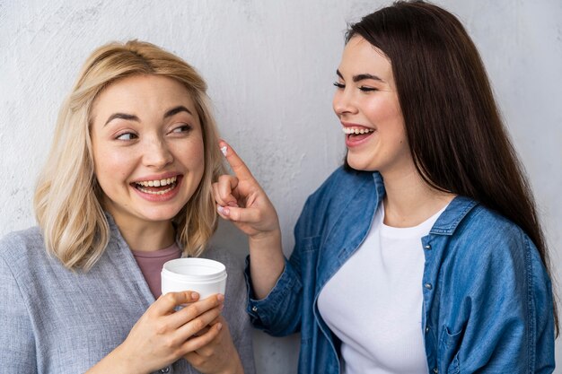 Portrait of happy women laughing and playing with moisturizer