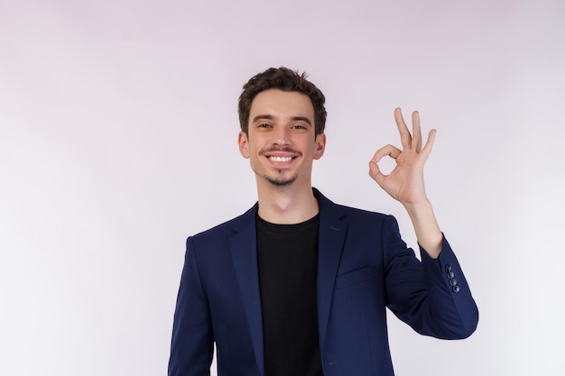 Portrait of happy young handsome businessman doing ok sign with hand and fingers over white background