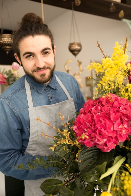 Free photo portrait of happy young male florist with flower bouquet