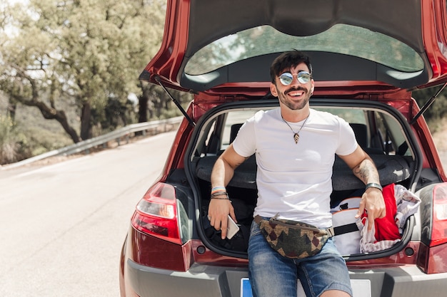 Portrait of happy young man standing near the car on road