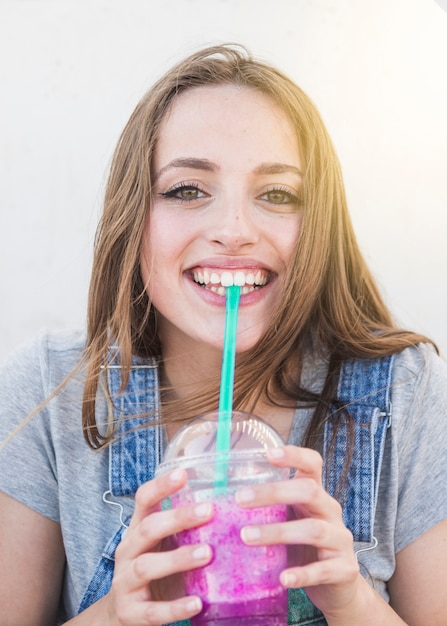 Free photo portrait of a happy young woman drinking juice