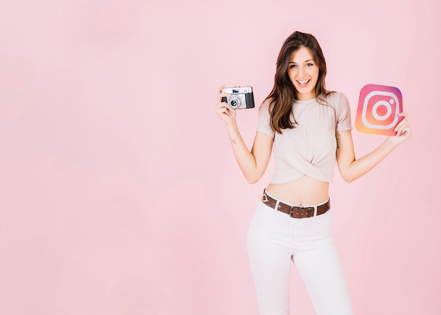 Free photo portrait of a happy young woman holding camera and instagram icon