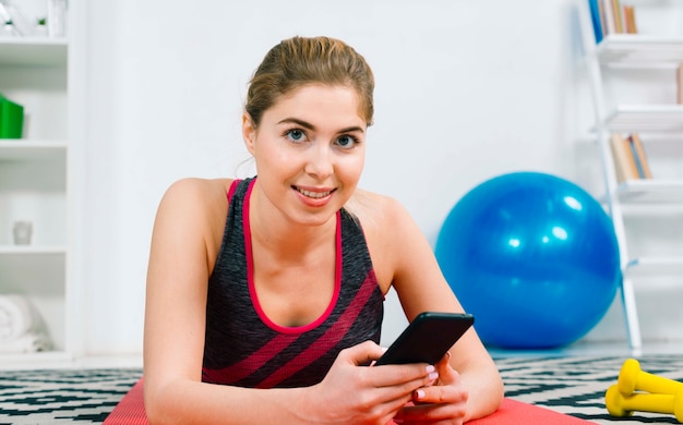 Portrait of a happy young woman holding mobile phone in hand looking at camera