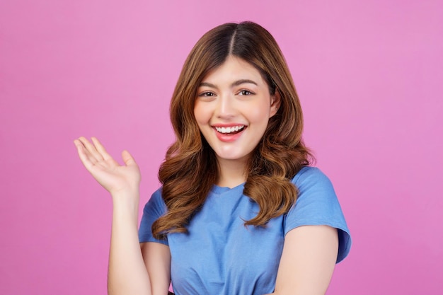 Portrait of happy young woman wearing casual tshirt waving hands isolated over pink background