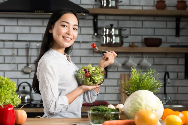 Portrait of healthy woman eating salad in kitchen