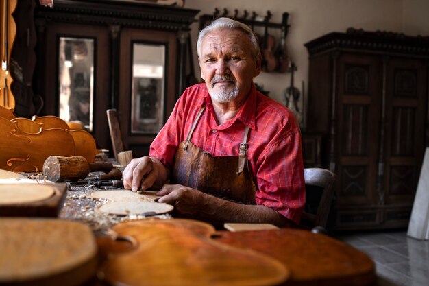 Portrait of highly experienced senior craftsman in his carpentry workshop with tools working on his projects