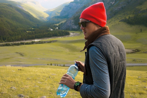 Portrait of hipster man traveling at mountains,wear red hat and hipster clothes,make pictures