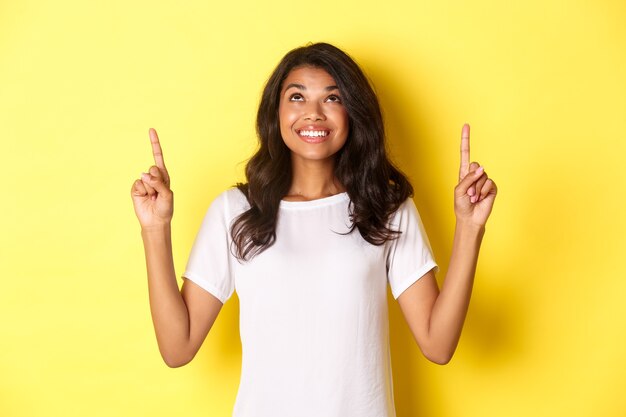 Portrait of hopeful africanamerican female student looking up and smiling excited standing