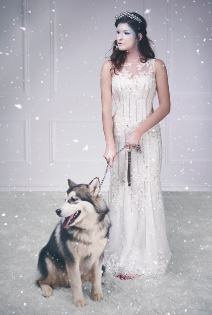 Portrait of ice queen and sled dog among snow falling