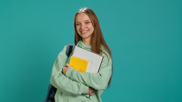 Free photo portrait of jolly pupil with school supplies in arms