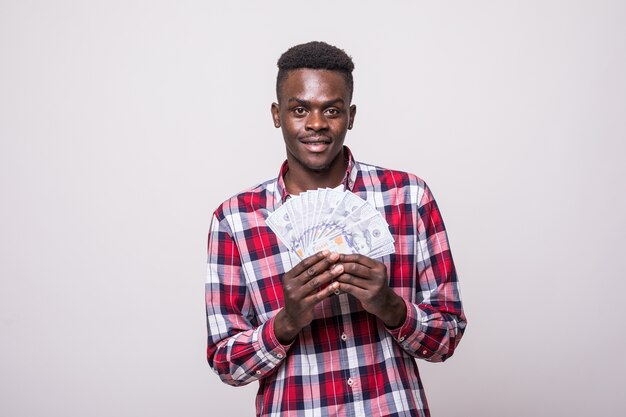 Portrait of a joyful excited afro american man holding money banknotes and looking isolated