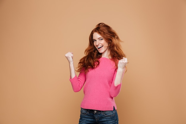 Free photo portrait of a joyful satisfied redhead girl celebrating victory