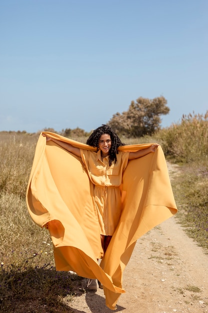 Portrait of joyful woman with yellow cloth in nature