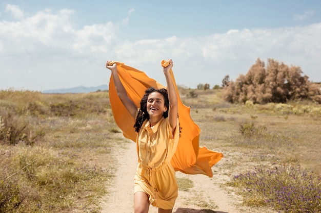 Portrait of joyful woman with yellow cloth in nature