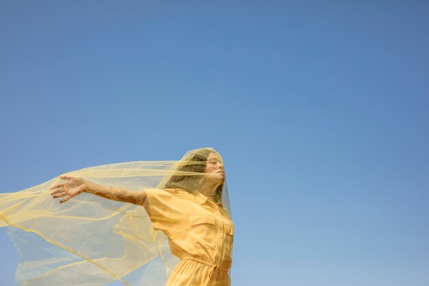 Portrait of joyful woman with yellow cloth in nature