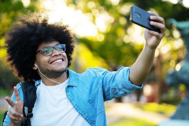 Portrait of latin man taking a selfie with his mobile phone while standing outdoors on the street