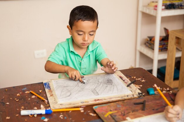 Portrait of a little boy working on a drawing for his art class at school