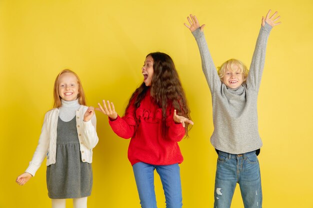 Portrait of little caucasian children with bright emotions isolated on yellow studio